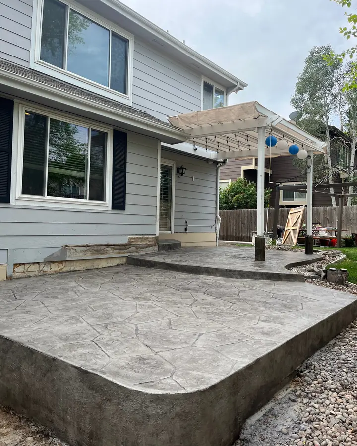 Stone-stamped patio with a raised edge behind a two-story house