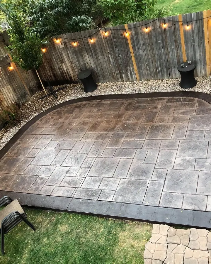 Ashlar-stamped patio with a dark border in a fenced backyard