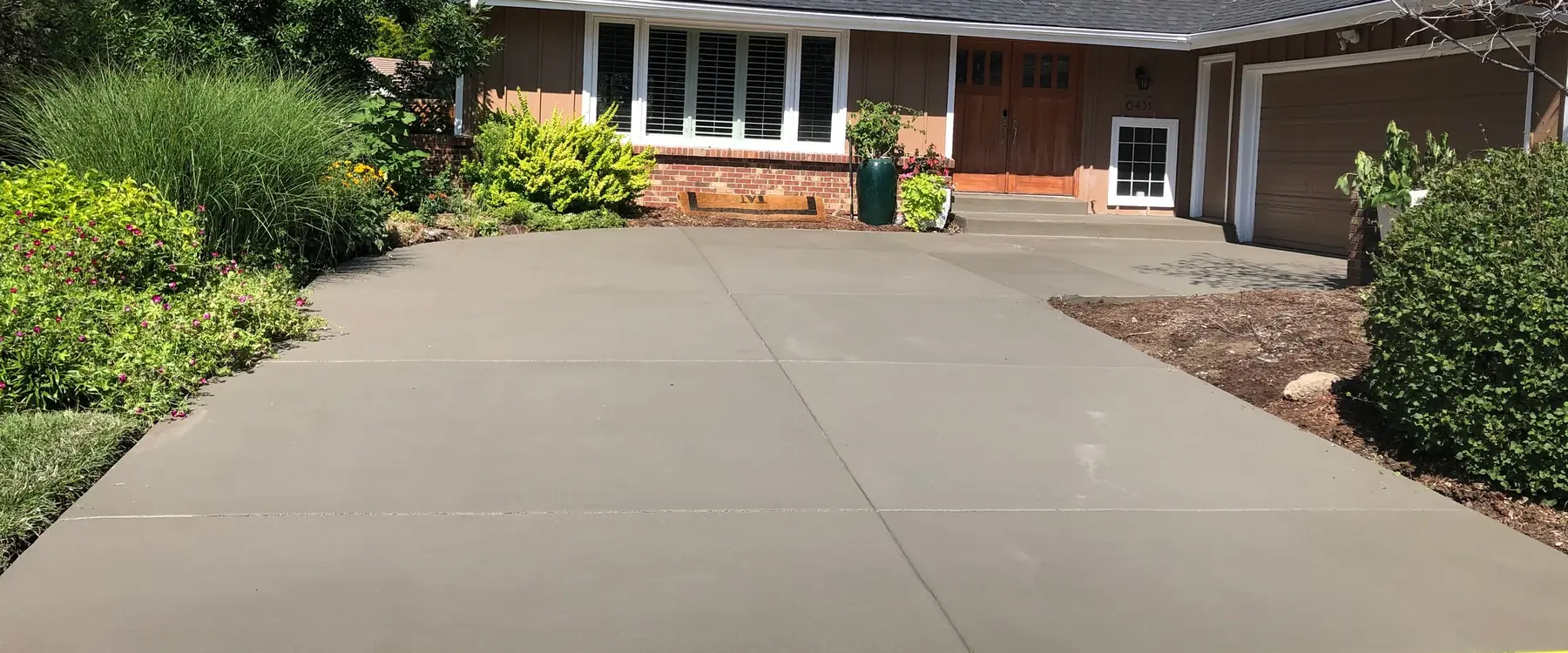 Broom-finished concrete driveway with control joints in front of a ranch house