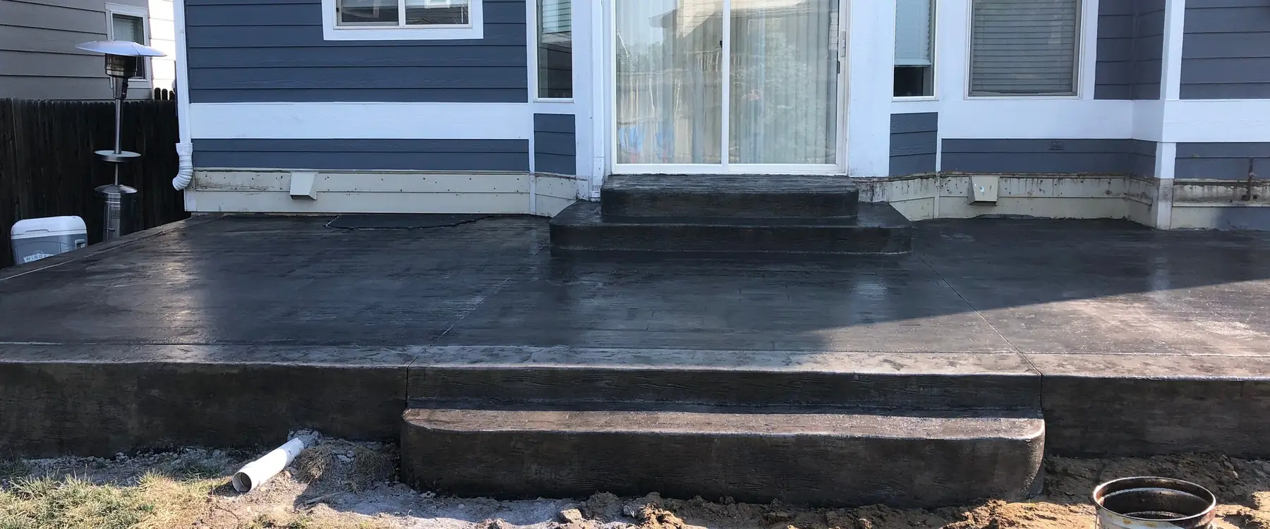 Charcoal stamped patio and step behind a blue house